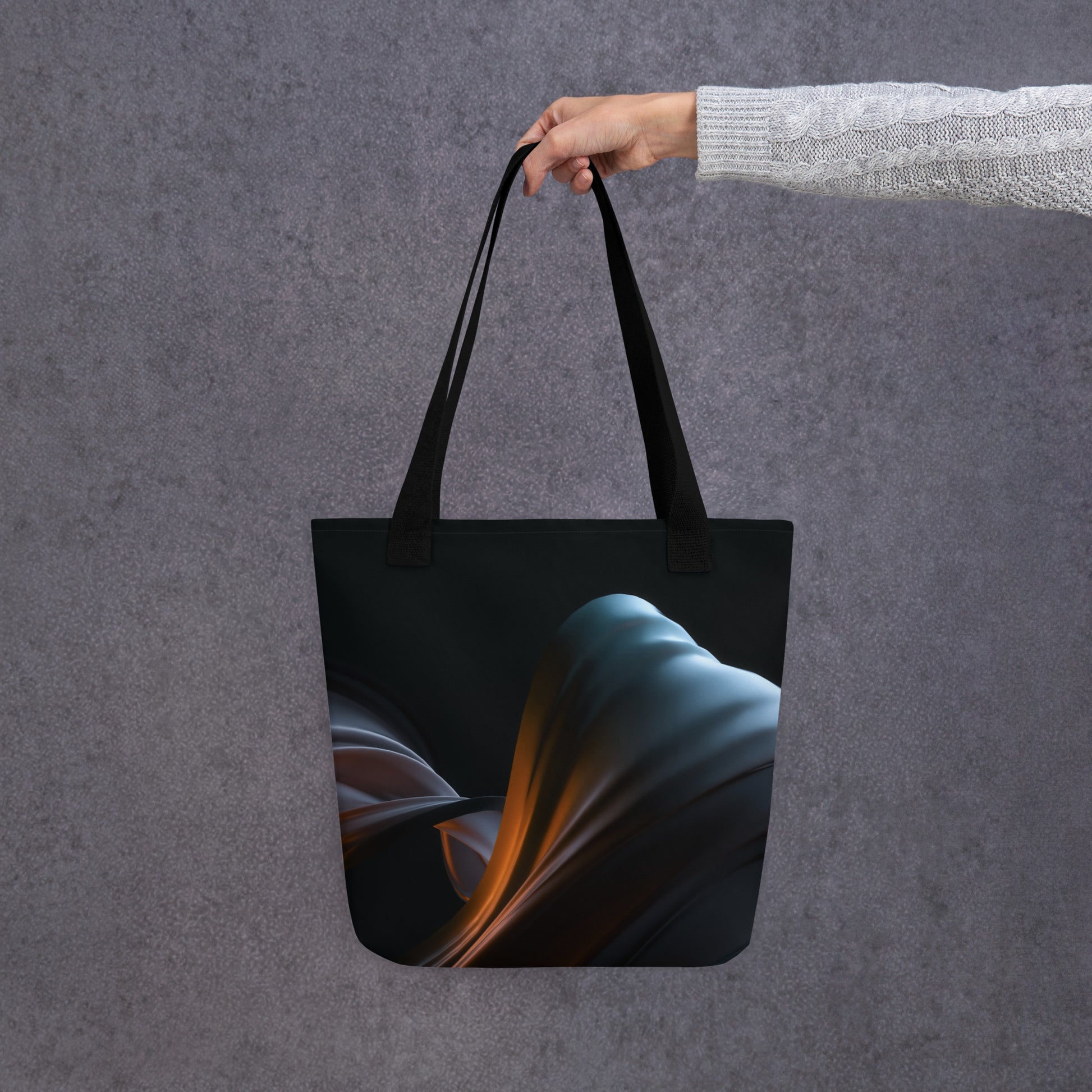 A person holding the HFT Tote Bag VI with an abstract artistic design in shades of blue and brown against a textured gray background.