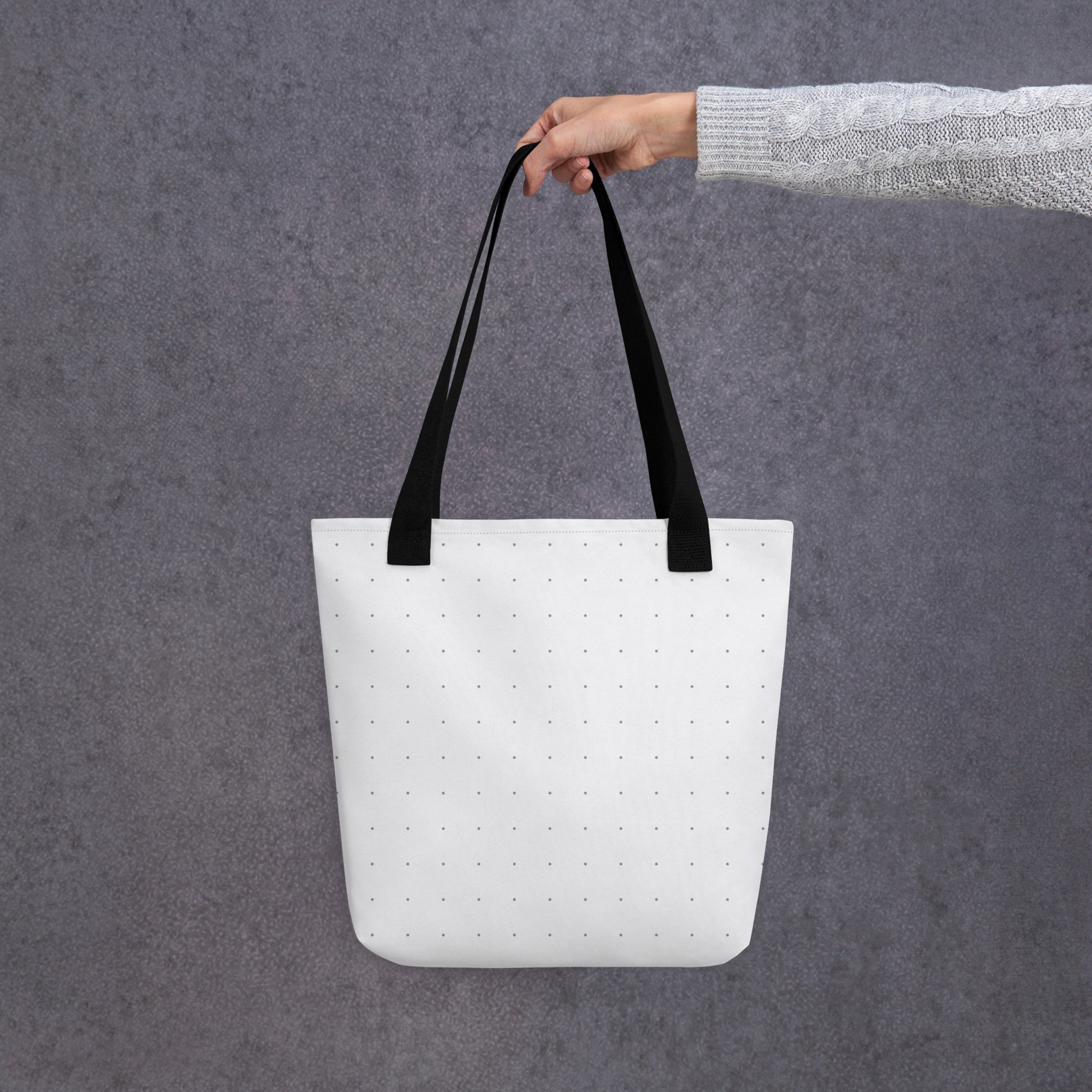 Person holding an HFT Tote Bag III, showcasing the bag's spacious and trendy design with a polka dot pattern against a concrete background