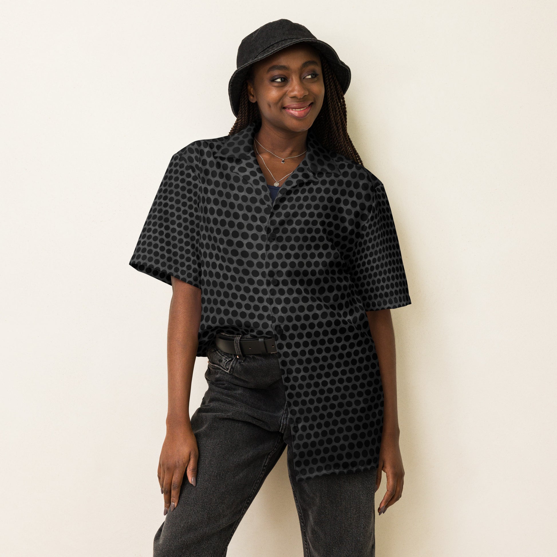 Unisex black button-up shirt with a subtle circular dot pattern, short sleeves, and a crisp pointed collar. front