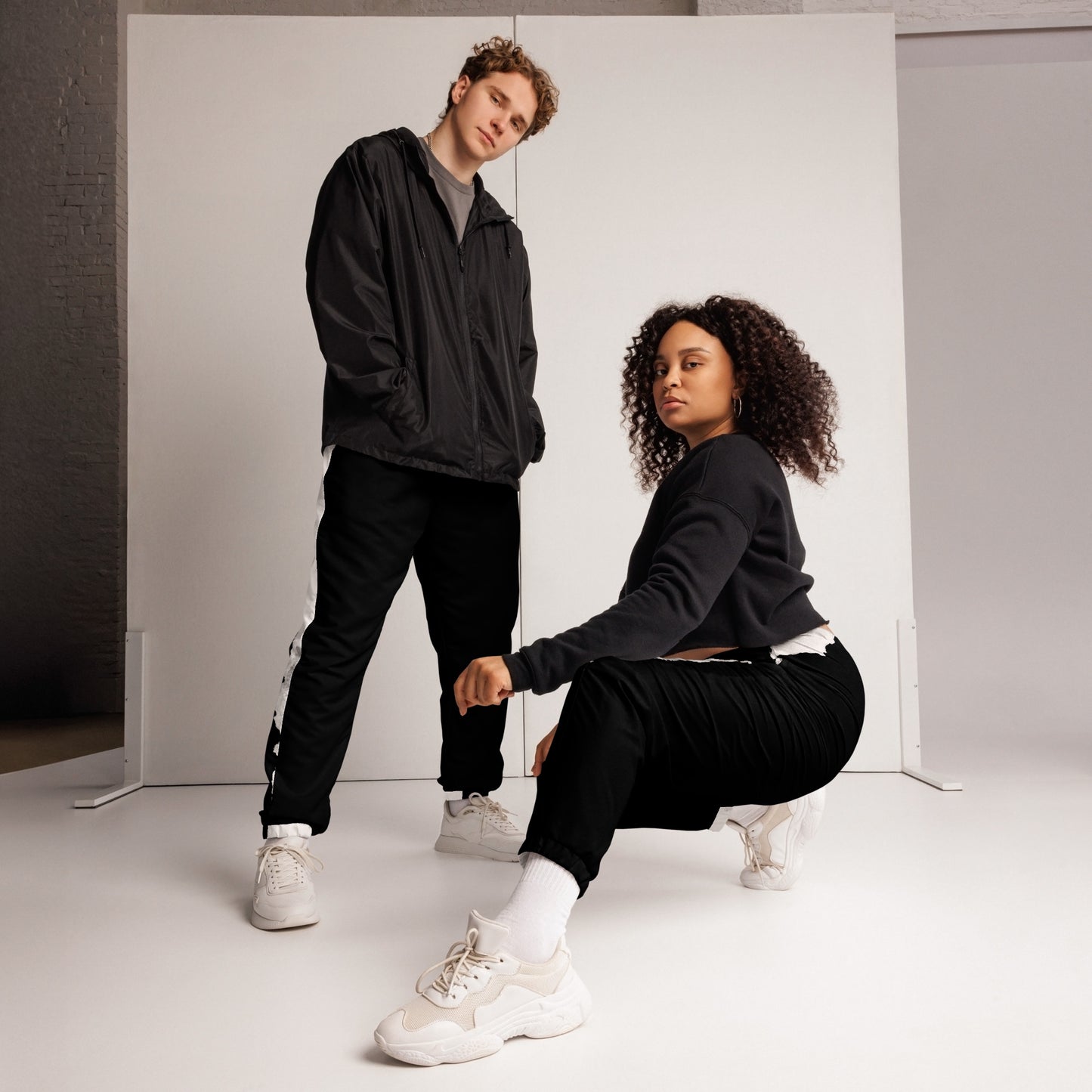 Stylish black and white HFT unisex track pants with water-resistant and lightweight fabric, featuring elastic ankle cuffs and mesh lining, laid flat two models