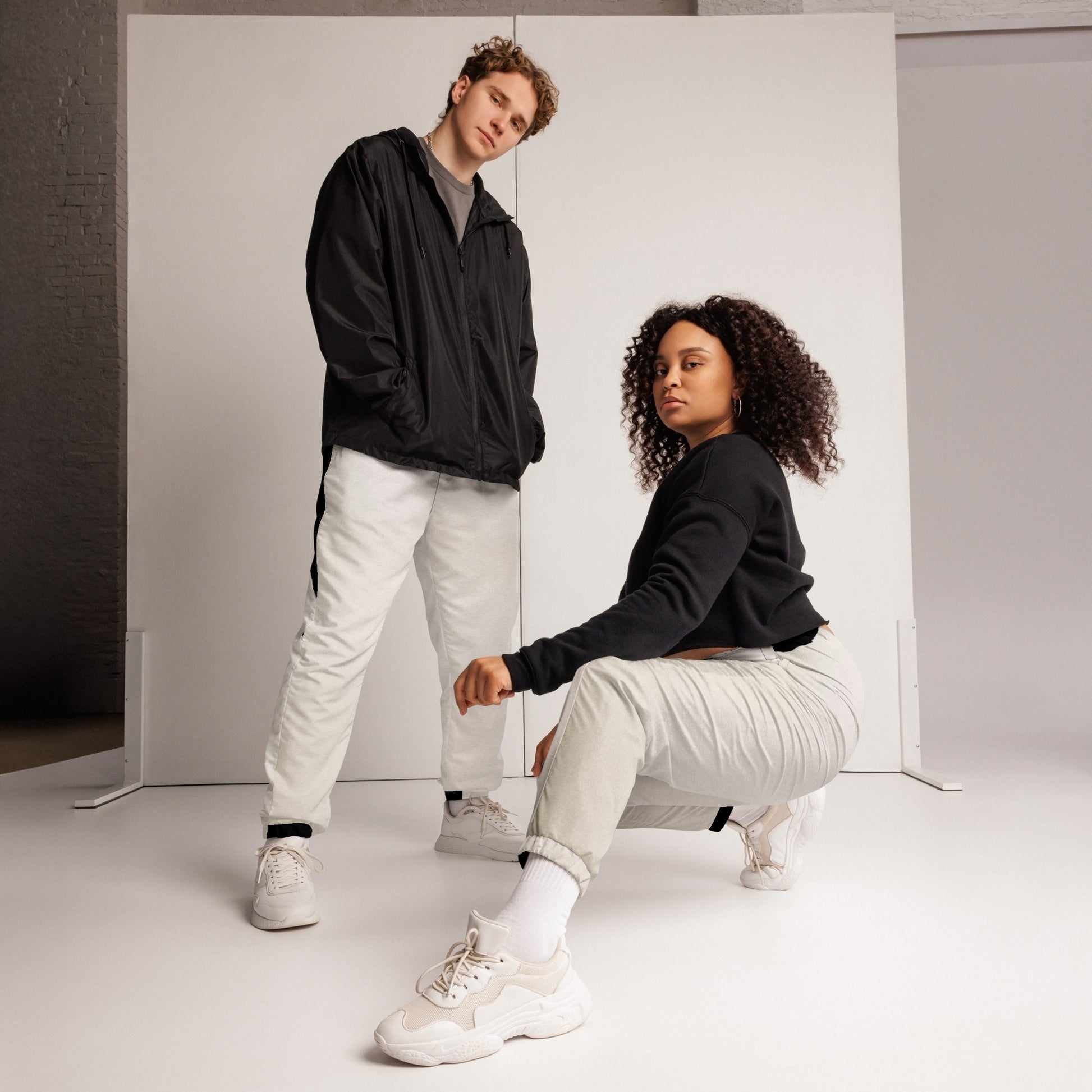 Pair of HFT Unisex Track Pants IV in a crisp white color with contrasting black side stripes, elastic waistband, and cuffs, laid flat on a white background 2 modes