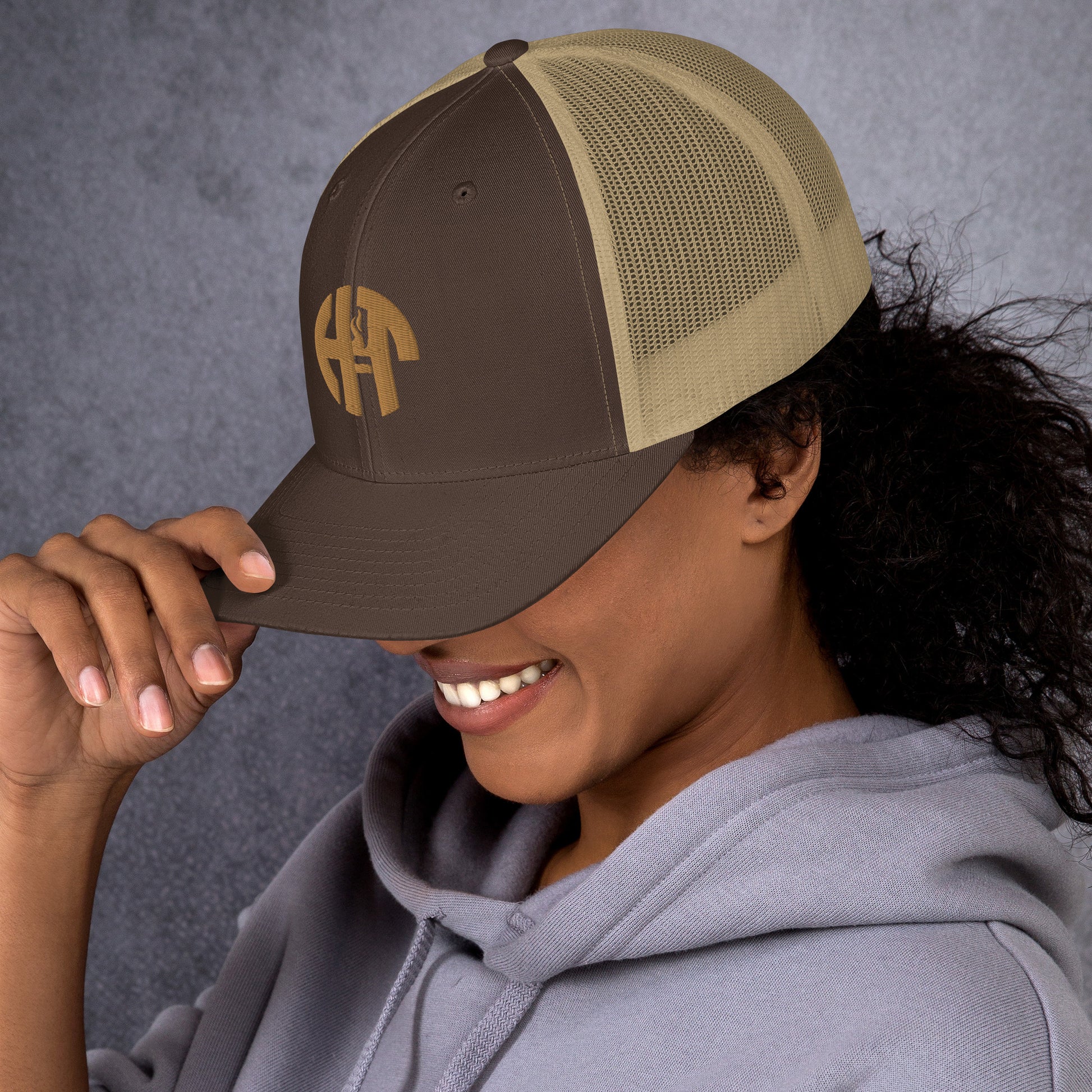 A stylish six-panel trucker cap with a breathable mesh back and a front panel featuring a black 'HFT' logo, complete with a pre-curved brim and an adjustable snap closure for comfort