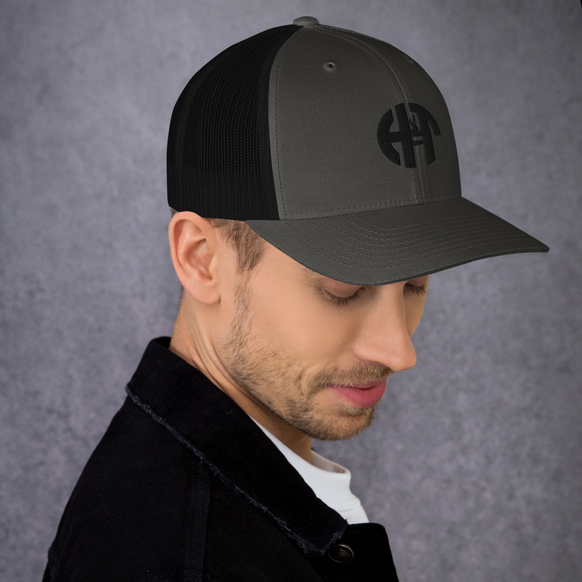 A stylish six-panel trucker cap with a breathable mesh back and a front panel featuring a black 'HFT' logo, complete with a pre-curved brim and an adjustable snap closure for comfort