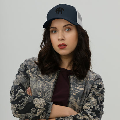 A stylish six-panel trucker cap with a breathable mesh back and a front panel featuring a black 'HFT' logo, complete with a pre-curved brim and an adjustable snap closure for comfort navy front