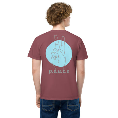 Person wearing the HFT Unisex Garment-Dyed Pocket T-shirt featuring a distinctive peace-sign hand graphic and the word 'p.e.a.c.e' printed on the back brick back