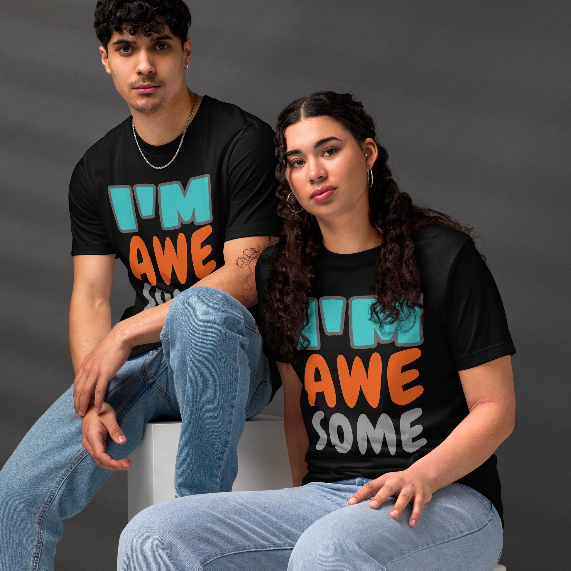 Couple wearing HFT Unisex Staple Eco T-shirts, with the man and woman’s black tee featuring the text I’m awesome' in multicolor