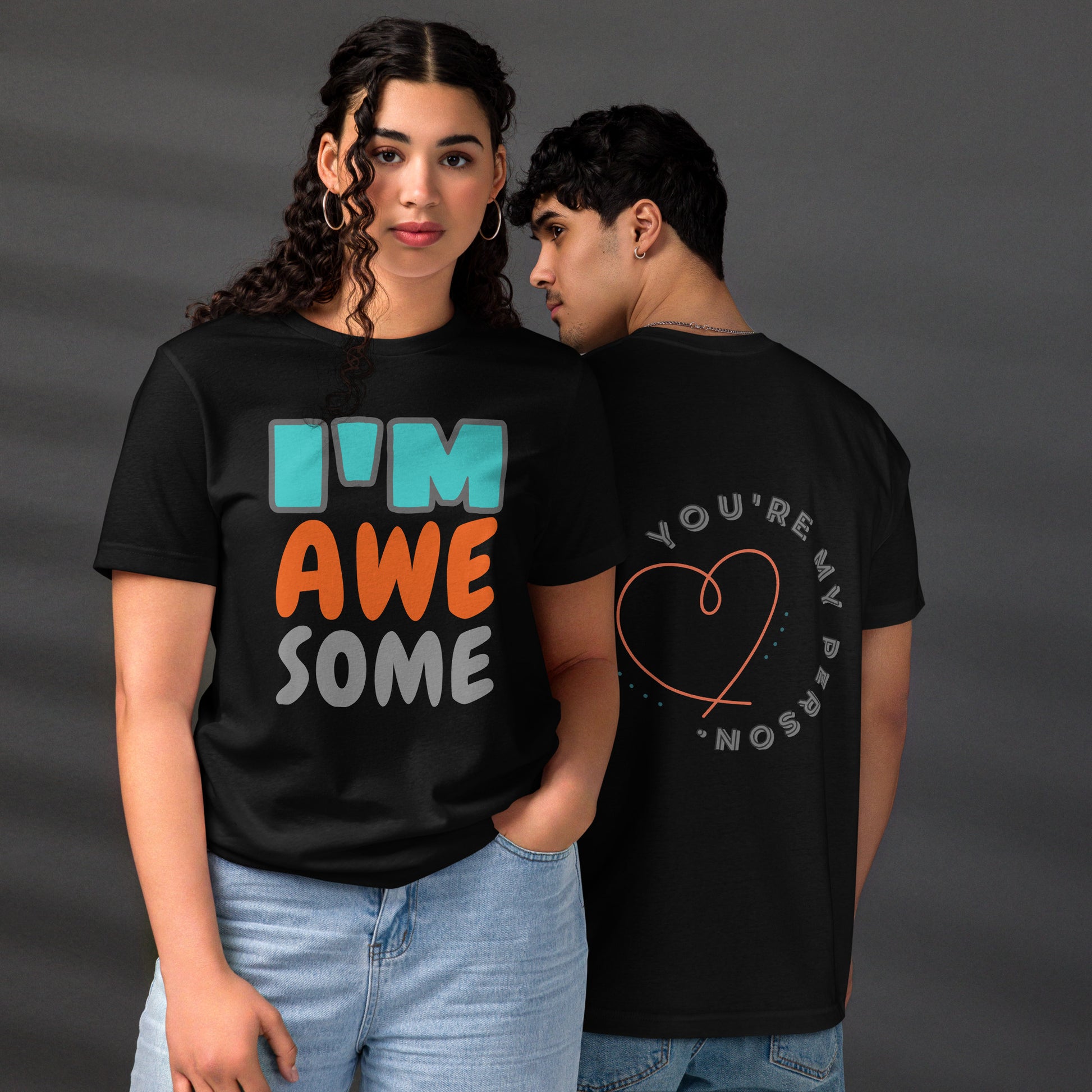 Couple wearing HFT Unisex Staple Eco T-shirts, with the man's black tee featuring the text 'you're my person' inside a red heart and the woman's black tee with the text 'I'm awesome' in multicolor