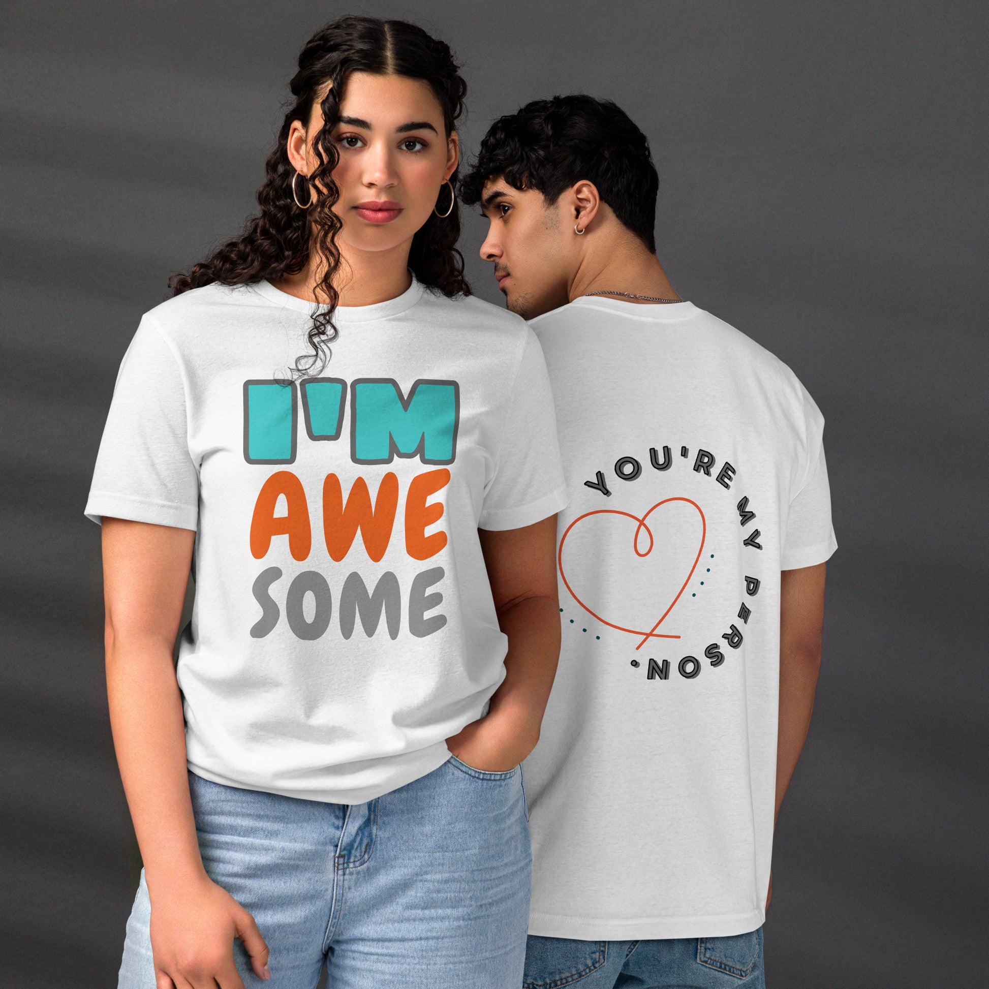 Couple wearing HFT Unisex Staple Eco T-shirts, with the man's white tee featuring the text 'you're my person' inside a red heart and the woman's white tee with the text 'I'm awesome' in multicolor