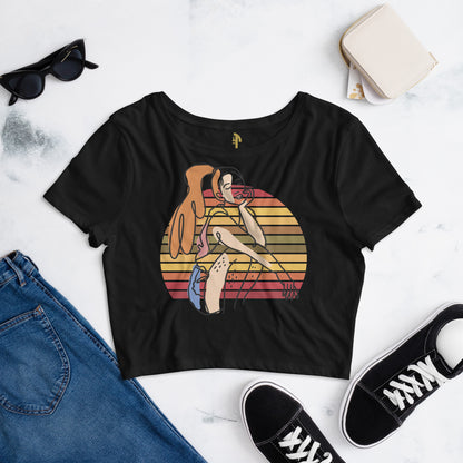 Black HFT Women's Crop Tee with a colorful, retro-inspired graphic print of a woman seated and wearing headphones, displayed on a flat surface