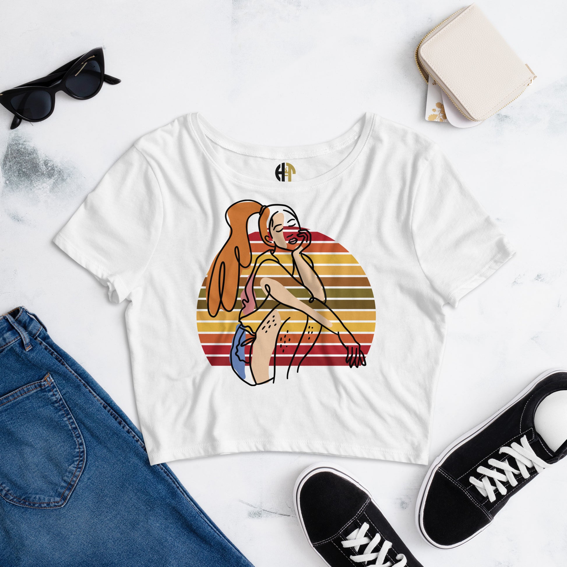 White HFT Women's Crop Tee with a colorful, retro-inspired graphic print of a woman seated and wearing headphones, displayed on a flat surface